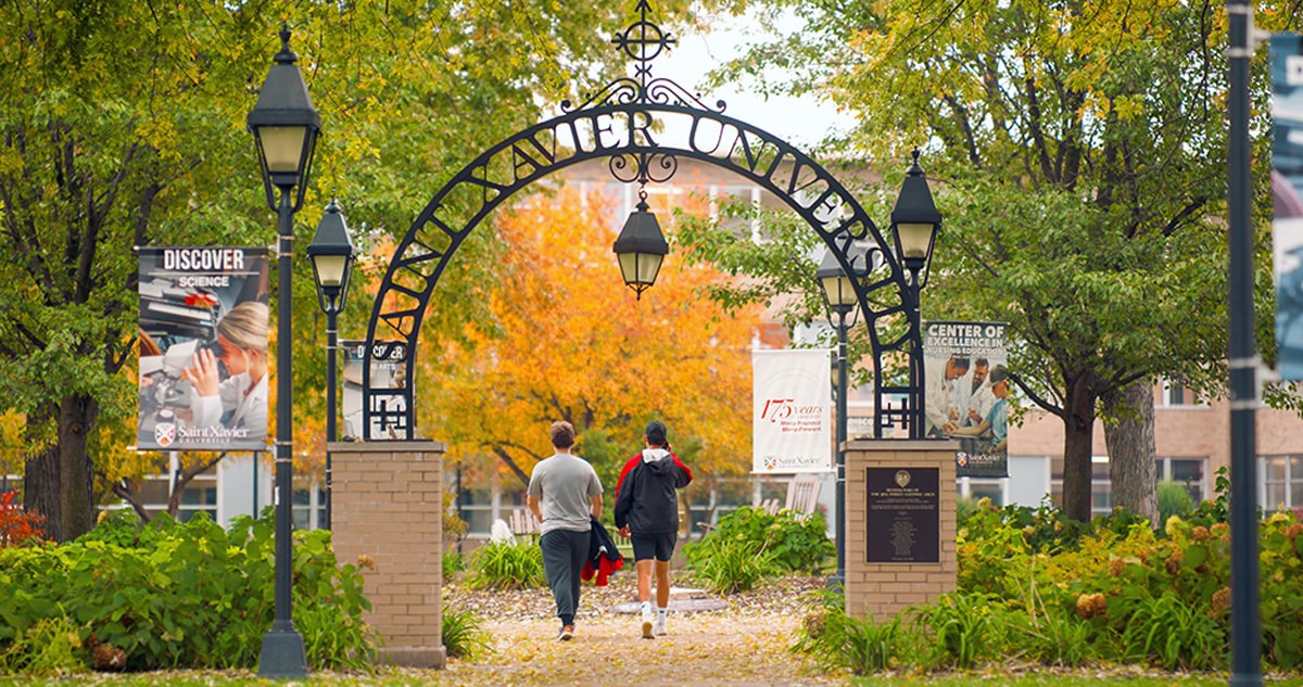 Two students walking under SXU arch