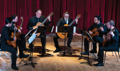 Group of five guitarist performing